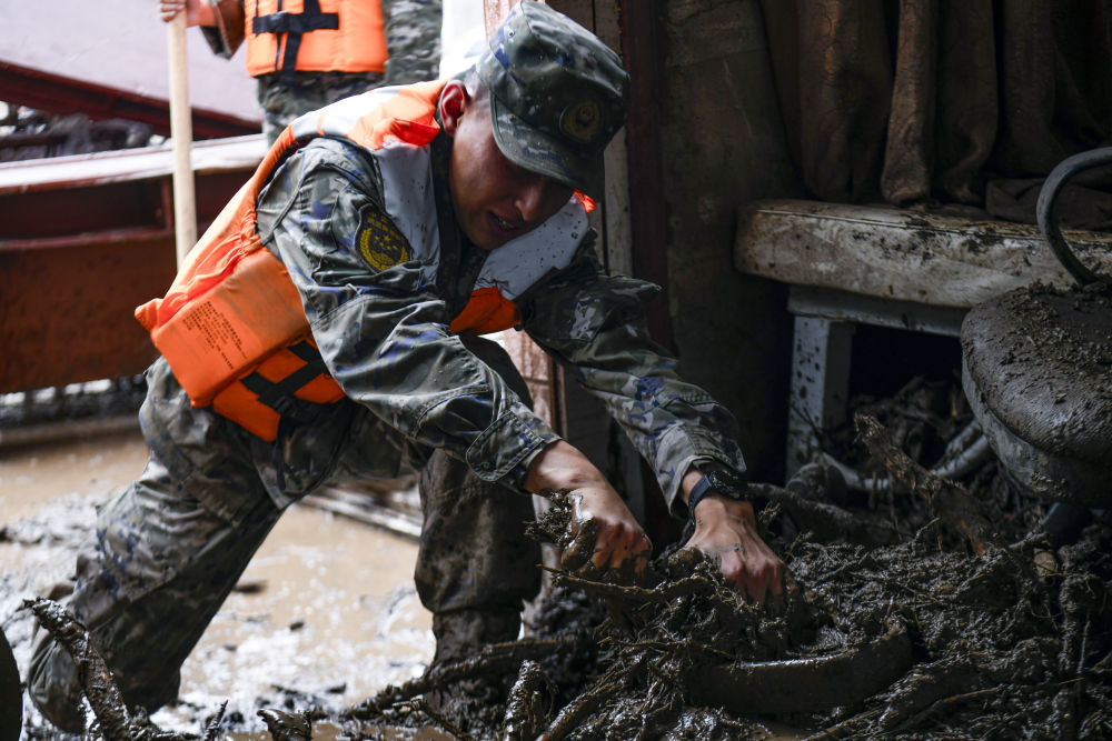 8月9日，武警甘肃总队机动支队官兵在兰州市榆中县城关镇兴隆山村受灾村民房间内清理杂物。新华社发（侯崇慧　摄）