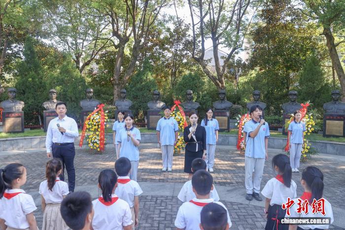 8月15日，江西南昌，南昌新四軍軍部舊址陳列館舉行紀念“‘8·15’日本宣布無條件投降80周年”活動，陳列館講解員與學生代表在新四軍早期領導人銅像前朗誦詩歌《英雄》。中新社記者 劉力鑫 攝