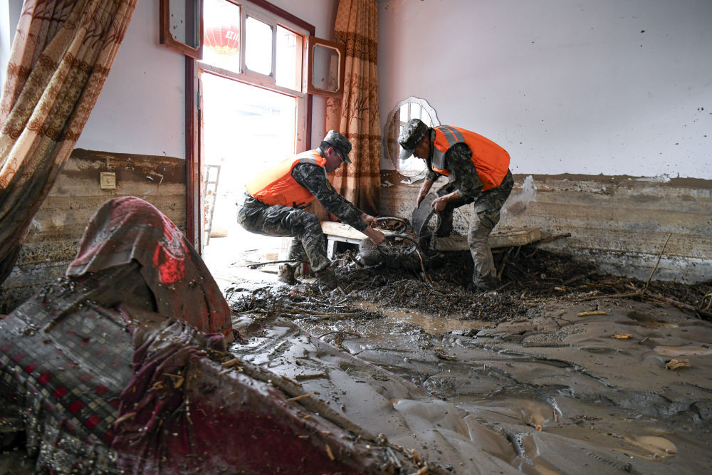 8月9日，武警甘肃总队机动支队官兵在兰州市榆中县城关镇兴隆山村受灾村民家中搬运物资。新华社发（侯崇慧　摄）