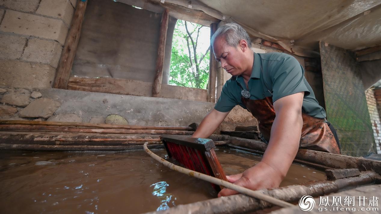 胡凤钰专注抄纸，纸浆池里的水波与他娴熟的动作呼应。李德宇　摄