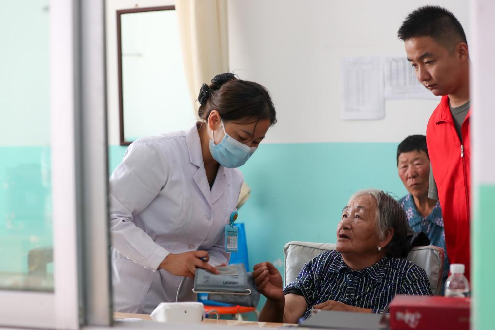 8月9日，在榆中县第三中学安置点医疗点，医护人员为受灾人员量血压。新华社记者　郎兵兵　摄