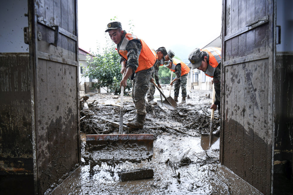 8月9日，武警甘肃总队机动支队官兵在兰州市榆中县城关镇兴隆山村清理淤泥。新华社发（侯崇慧　摄）