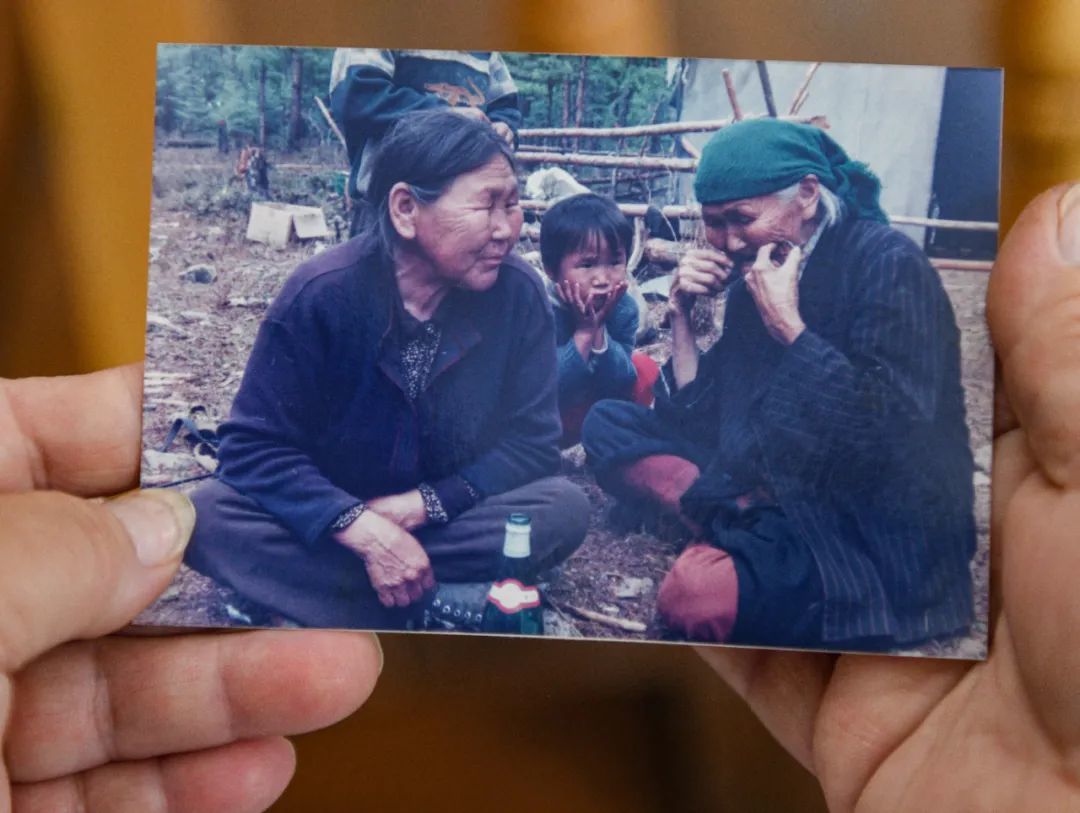 玛力亚·索的儿子何协手中的老照片,拍摄于1998年夏。玛利亚·索在猎民点内为时年三岁的外孙女乌云吹奏口弦琴,她的朋友芭拉杰依围坐在一旁静静聆听。