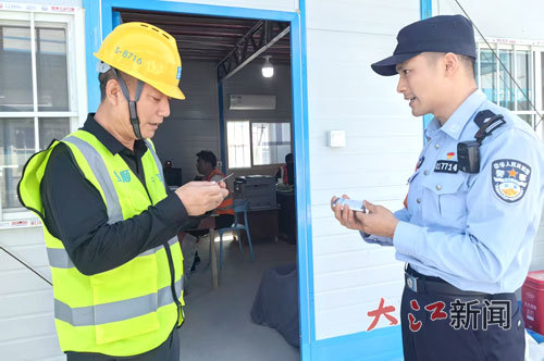 “项目警长”给工人发放宣传提示卡。