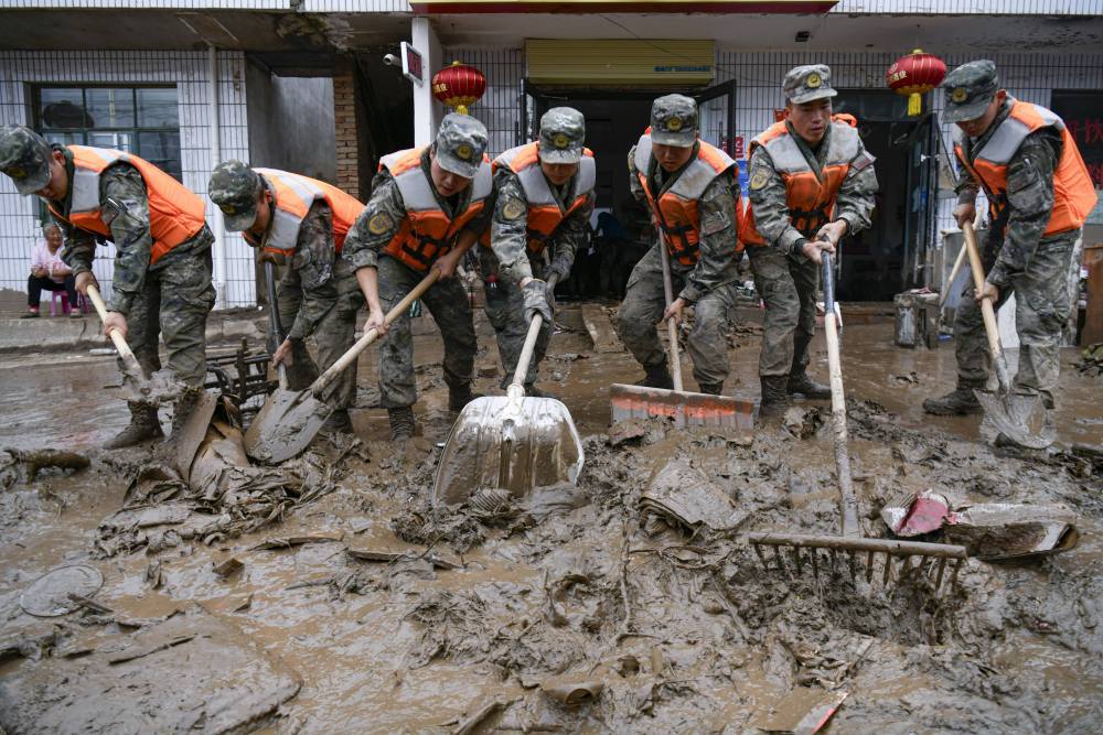 8月9日，武警甘肃总队机动支队官兵在兰州市榆中县城关镇兴隆山村清理淤泥。新华社发（侯崇慧　摄）