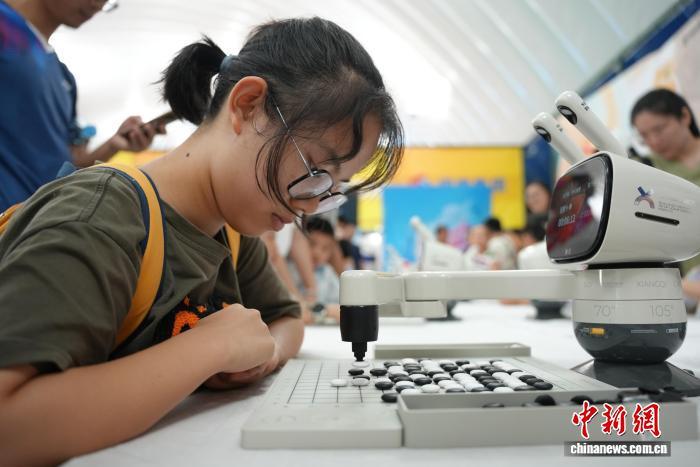 圖為圍棋機器人與青少年對弈。 吳敏 攝