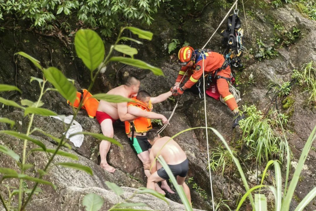 3消防员在另2名游客的帮助下给受伤游客绑安全绳和吊带.jpg