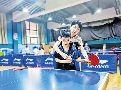 8月6日,在秦皇岛市全民健身中心,孩子们在教练指导下打乒乓球。 本报记者 张 辉摄