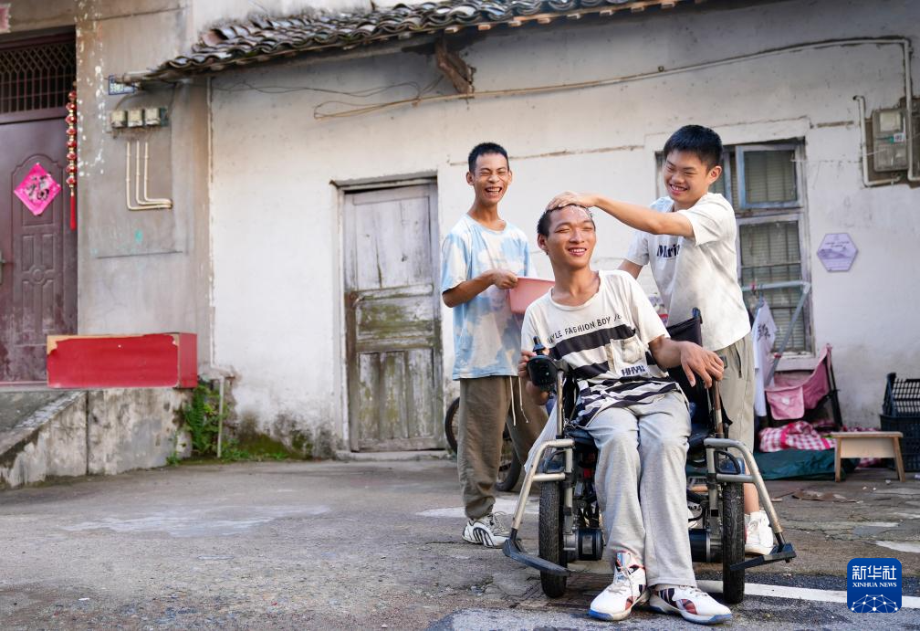 “小寒”（左）和“小琪”（右）在家门口帮小龙洗头。新华社记者胡晨欢 摄