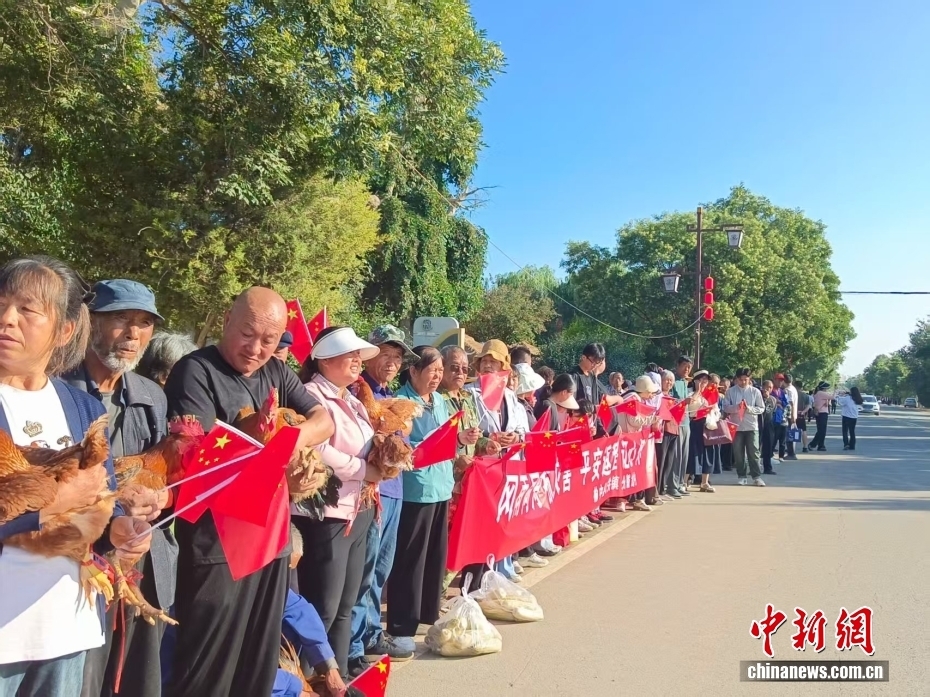 老乡抱着大公鸡送别救援人员　金小红　摄