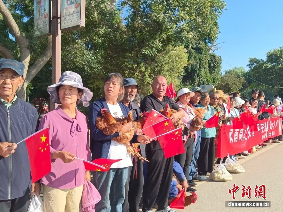 老乡抱着大公鸡送别救援人员　金小红　摄