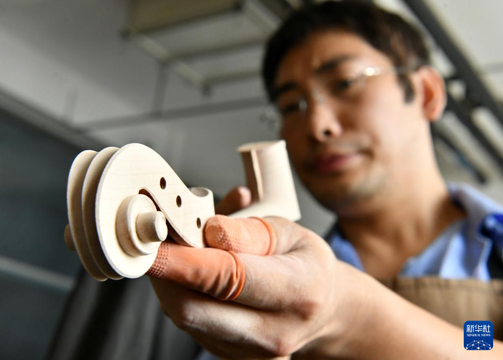 8月19日，工人在河北省肃宁县一家乐器生产企业车间内制作小提琴部件。