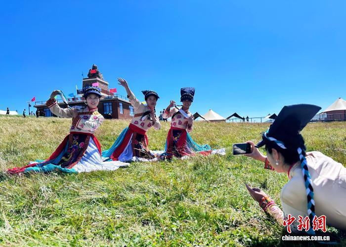 身着民族服饰的游客在草原上打卡留念 高展 摄