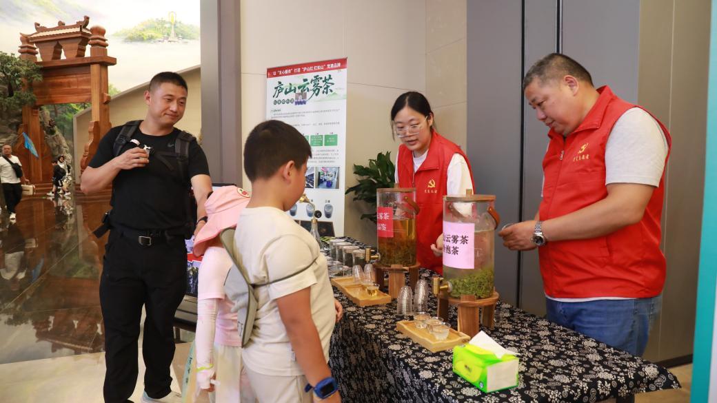 游客在庐山云雾茶摊位前品尝茶水。