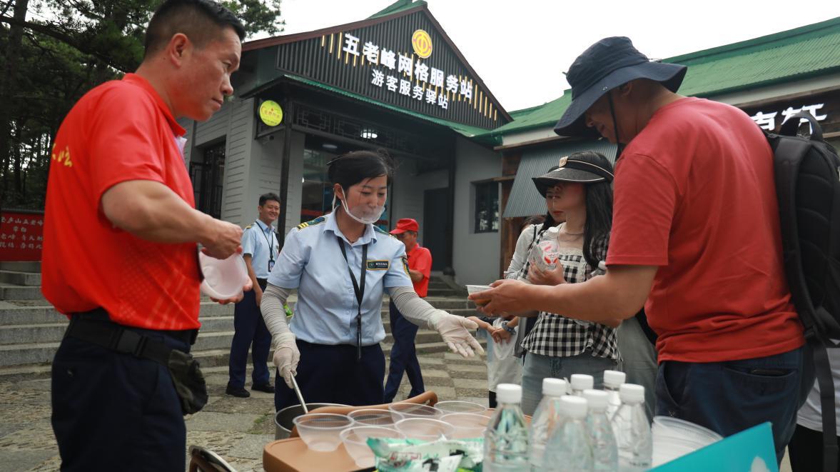 志愿者免费供应消暑饮品给过往游客。