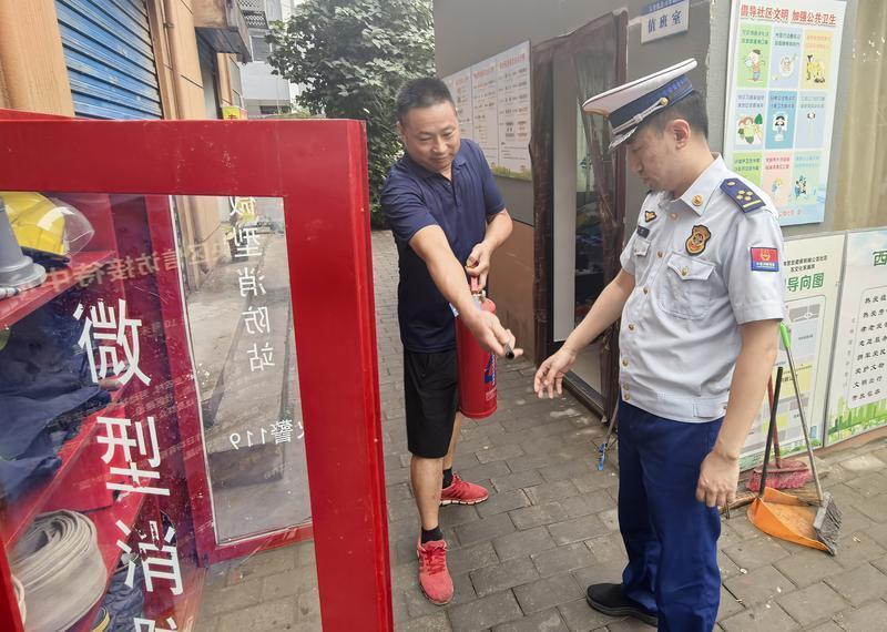 消防人员深入辖区微型消防站指导居民正确使用灭火器。