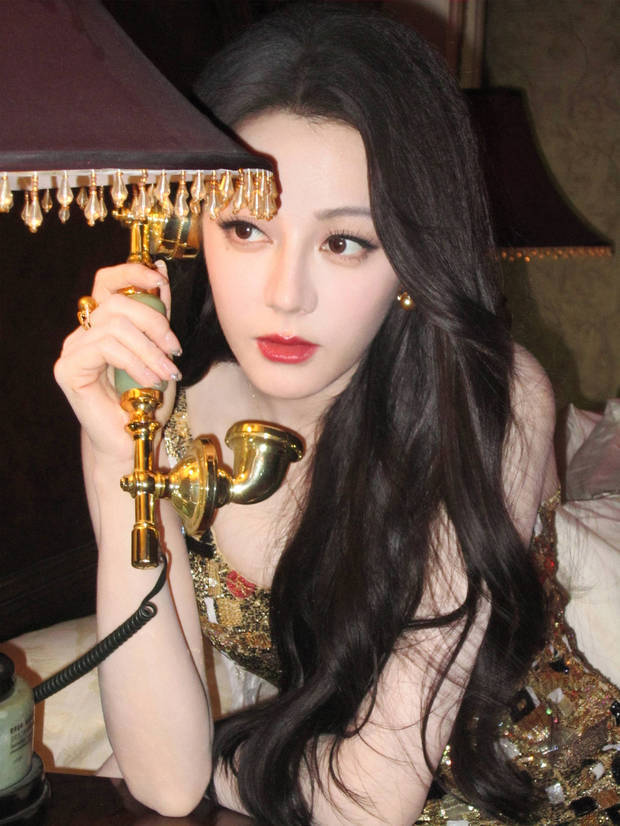 搜狐娱乐讯 24日，迪丽热巴参加活动的一组写真美照释出，她身穿鎏金闪片吊带裙光彩照人，手持金色电话秒变复古大美女，超养眼！