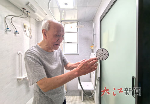 胡仪仲老人演示如何使用淋浴头。