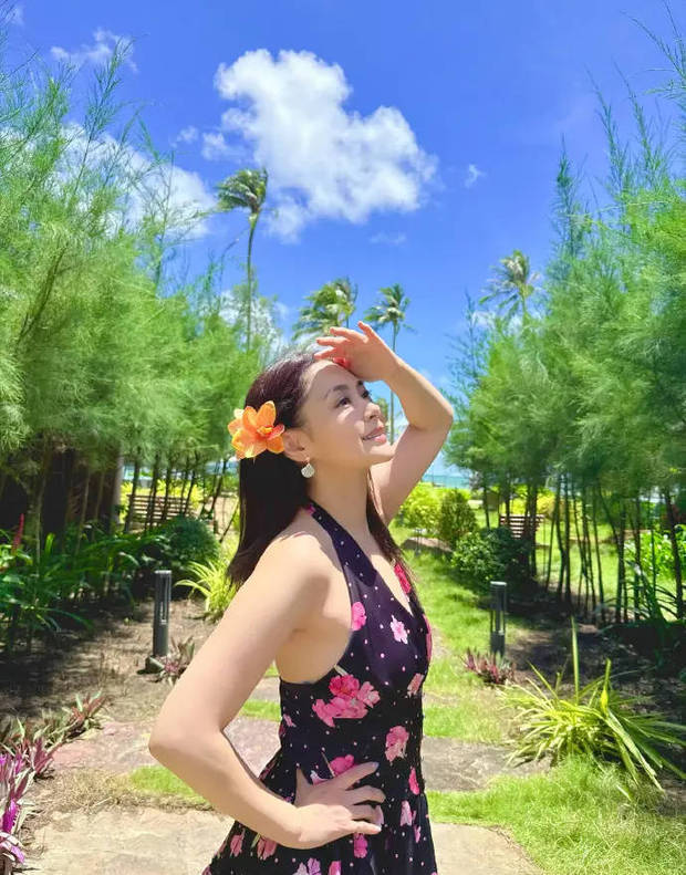 钟欣潼穿碎花挂脖裙，发别橙花，手搭额头眺望。