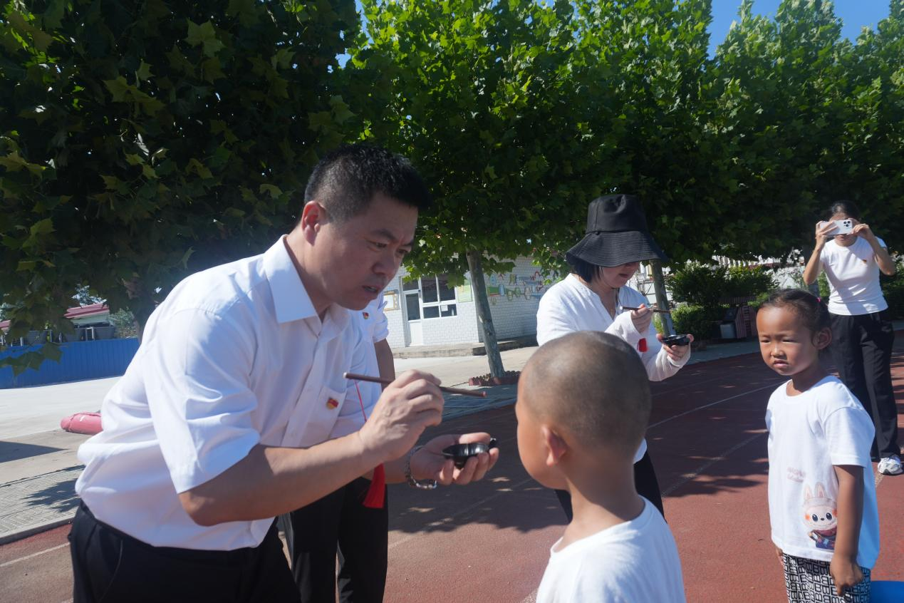 （图为校长为学生点 “朱砂痣” 启智 朱李男摄）
