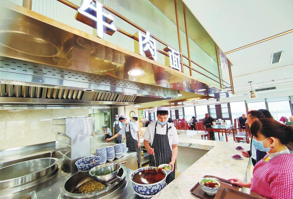 兰州一家老字号牛肉面馆里，工作人员正在给顾客捞面。