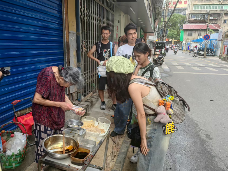 游客在“一毛钱”奶奶摊位前购买