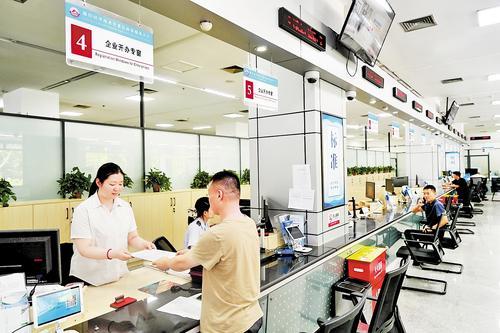 8月25日,廊坊开发区政务服务大厅,廊坊开发区行政审批局工作人员(左)在接待办事群众。