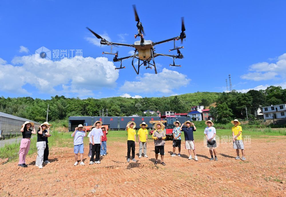 在萍鄉市湘東區排上鎮北村村水稻制種基地，戴中華（右五）指導學生使用無人機。
