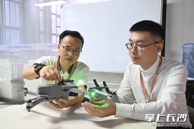 文宏成（左）和员工在一起讨论业务。长沙晚报全媒体记者 余劭劼 摄