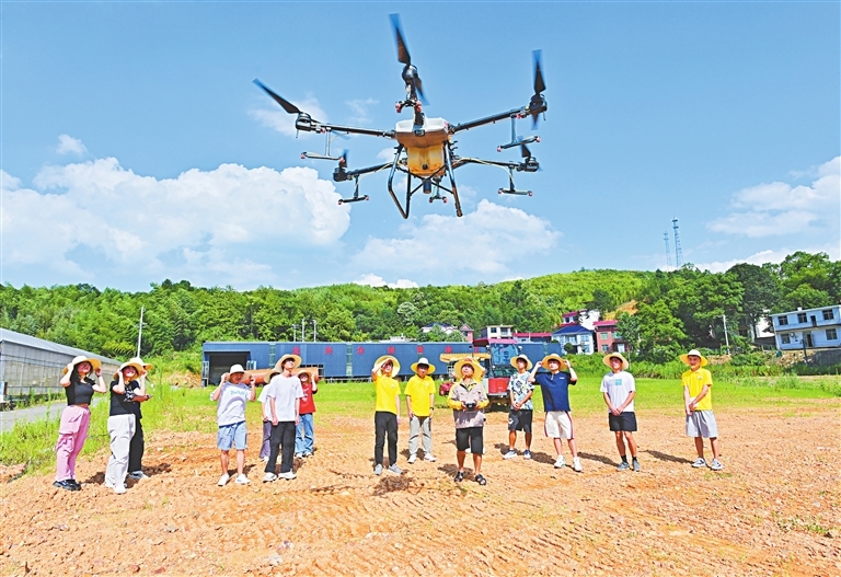 在萍鄉市湘東區排上鎮北村村水稻制種基地，戴中華（右五）指導學生使用無人機。