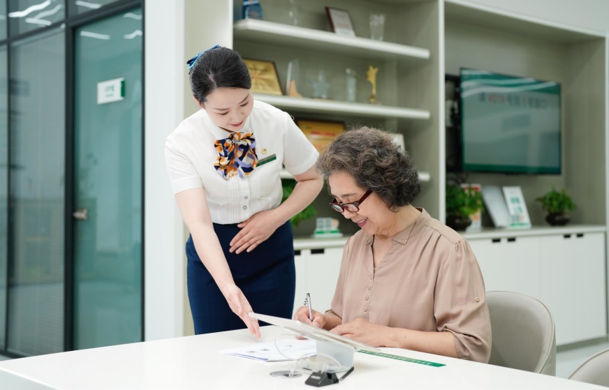 图：柜面服务人员为老年人办理保单业务