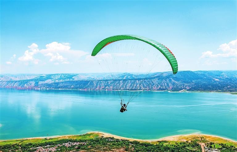 在碧波万顷的永靖县黄河三湾景区，游客正体验滑翔伞项目。新甘肃&middot;甘肃日报记者　田蹊