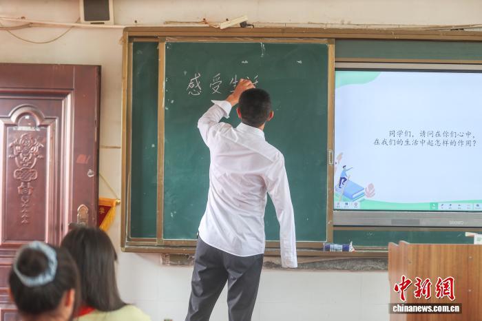 图为乌城小学校长方根水在讲台上用左手写板书。刘力鑫 摄