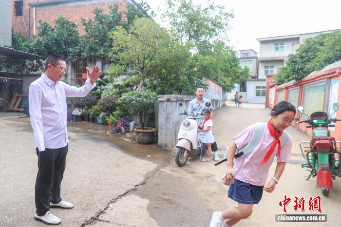图为在江西省南昌市新建区石埠镇乌城小学，校长方根水在校门口迎接学生到校。刘力鑫 摄