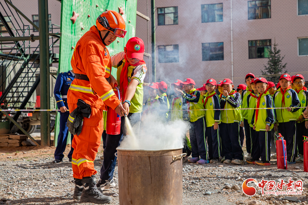 消防队员正在协助学生进行干粉灭火器的使用