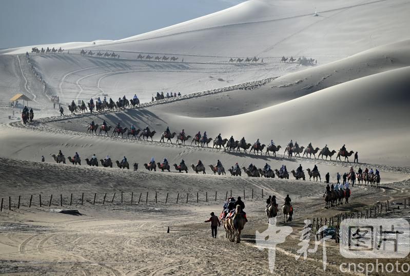 2025年9月6日，金秋时节，游客在甘肃省敦煌市鸣沙山月牙泉景区游览，体验丝路风情。中新社发　张晓亮　摄