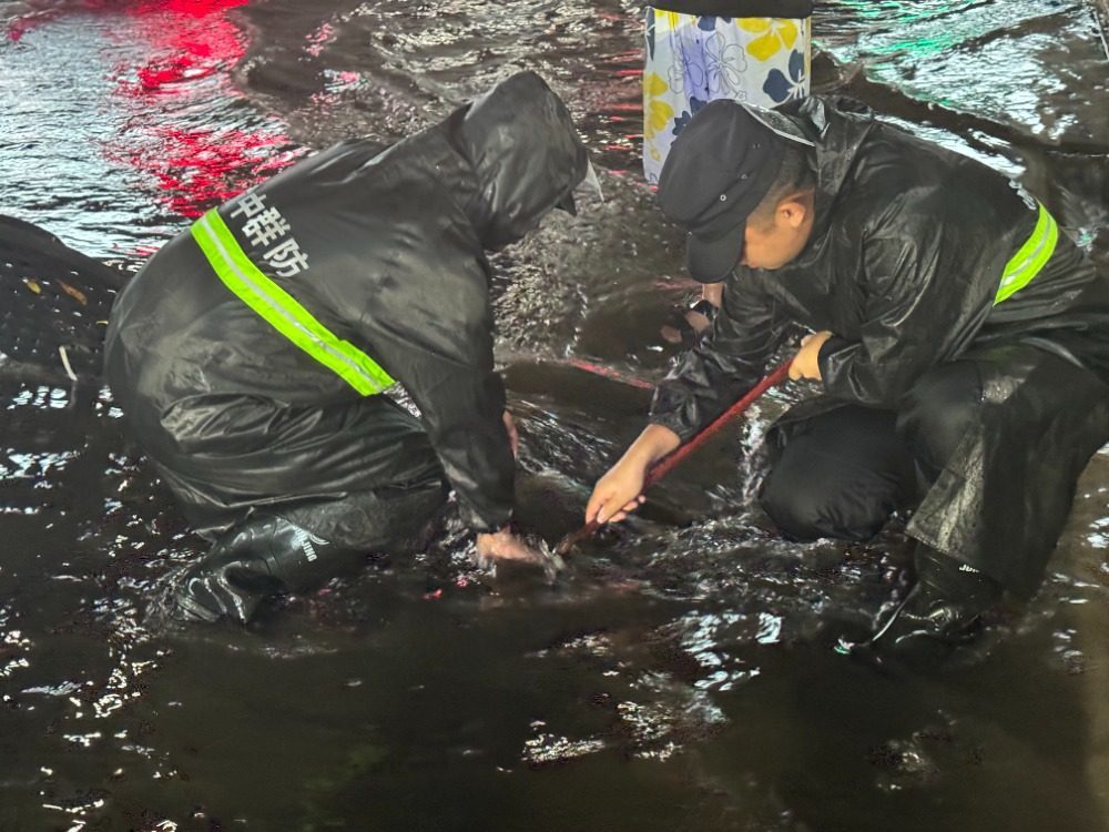 渝中区曾家岩轨道站外，群防人员在积水中进行清掏作业。受访者供图