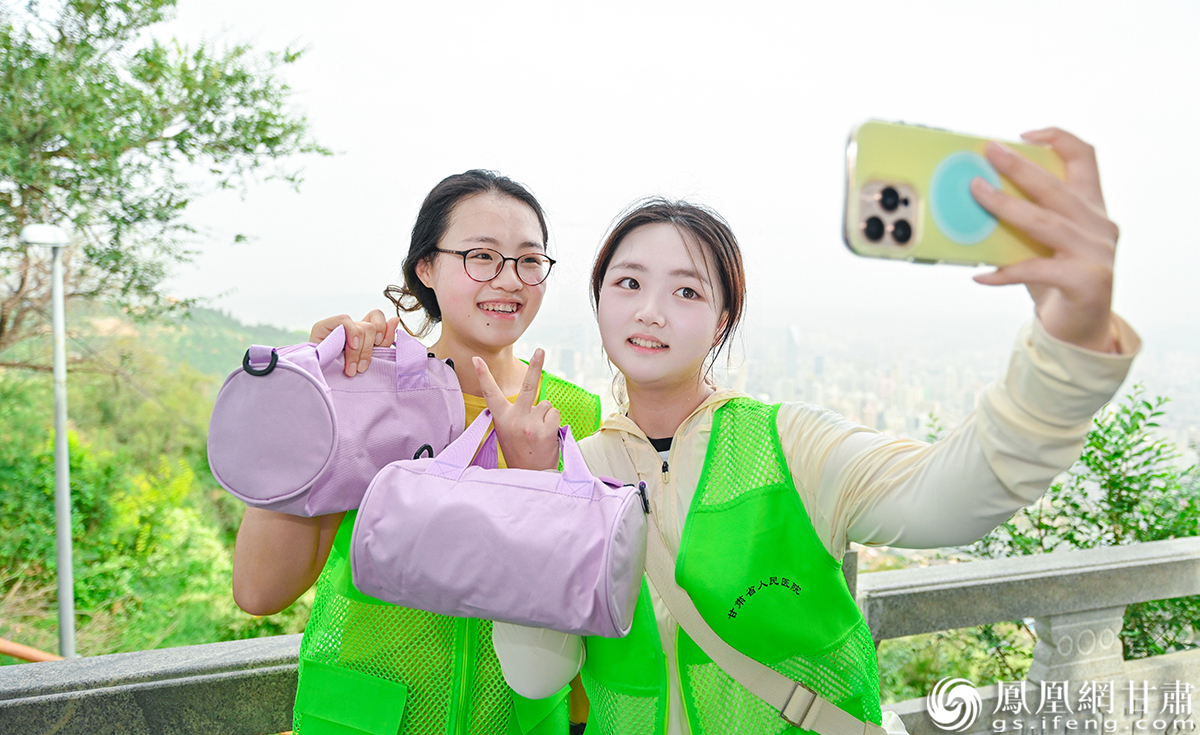 登山者手持泰康养老甘肃分公司赠送的纪念品拍照打卡
