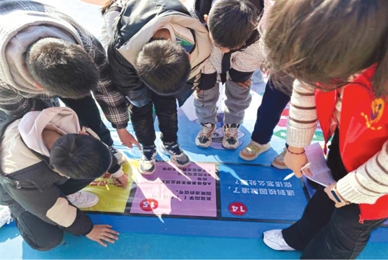 郑州大学法趣团队成员深入乡村小学带领小朋友玩法治飞行棋游戏。