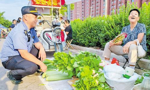 9月4日下午，晋州市文苑路潮汐市场上，该市城管执法局执法队员谢大帅蹲下来，与摆摊的田阿姨唠起嗑。本报记者 蔡晓辉摄