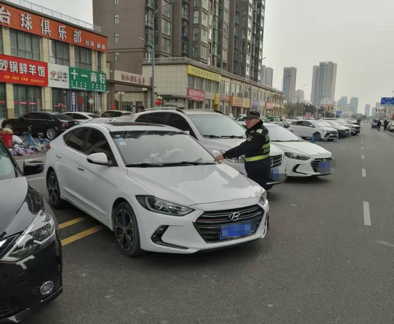 执法人员对岷江路的违停车辆张贴提示单