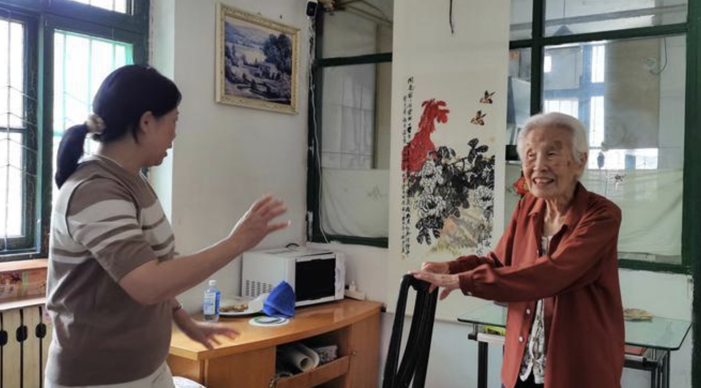 朱梅(左)和老人商量在客廳里裝個扶手,方便她日常鍛煉。