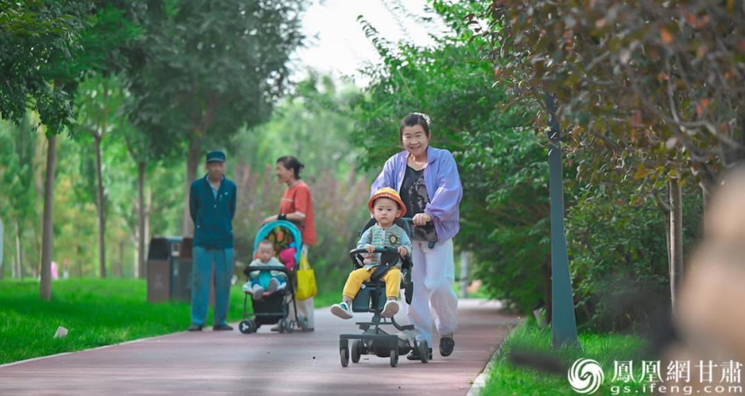 刘翠英（右）推着孙子在带状公园漫步，幸福笑容洋溢在脸颊。
