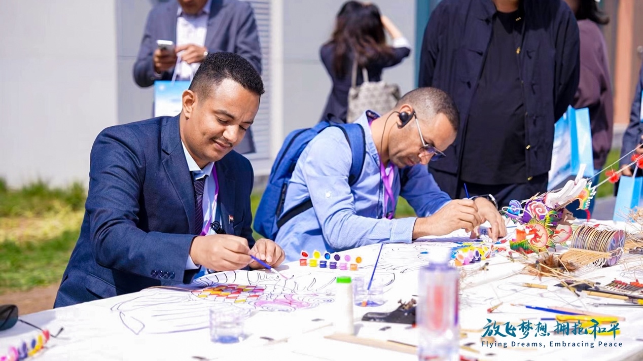 （参会嘉宾参与体验风筝制作环节）