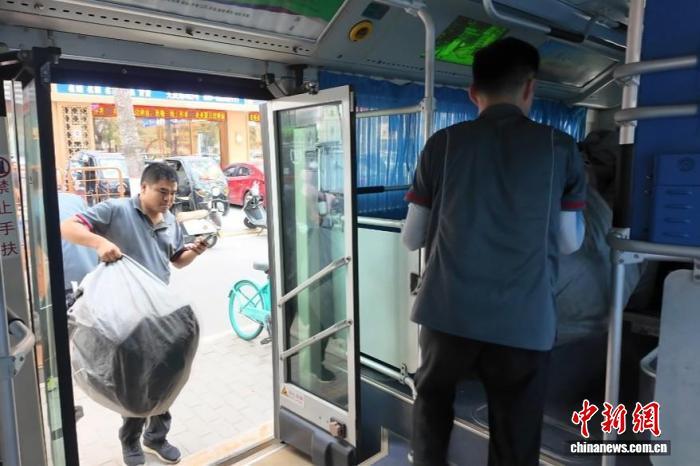 图为物流工作人员将快件搬运至公交车辆内。　梅镱泷 摄