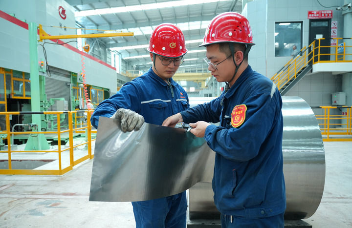在湖南涟钢电磁材料公司轧钢作业区，首卷“手撕钢”下线，工作人员正在测量板卷厚度。（受访者供图）