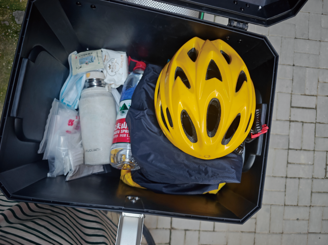 我的外卖箱子,里面会放着晚上回家穿的外套、雨衣、一次性口罩和防水手机套、感冒药、肠胃药、卫生巾,防雨鞋套,还有人脸识别用的全盔