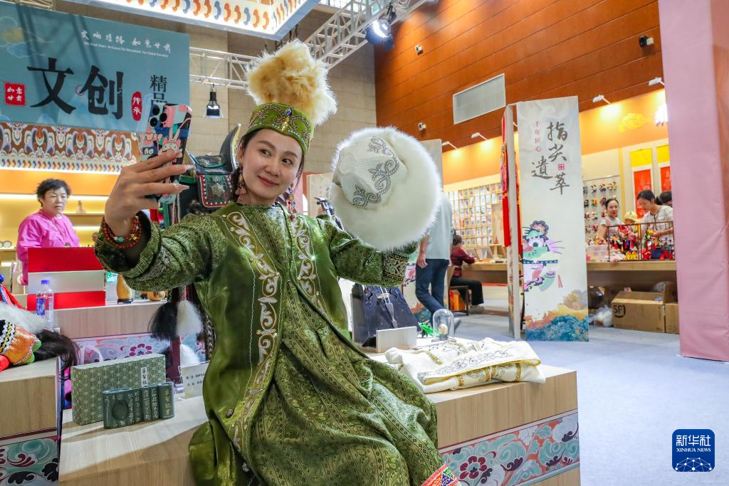 9月22日，游客在敦煌文博会上的一个展览现场身穿民族服饰自拍。