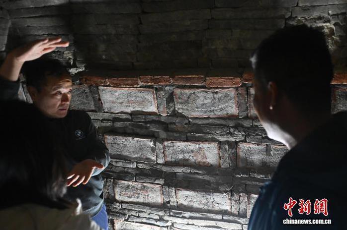 9月24日,在位于甘肃省嘉峪关市的嘉峪关新城魏晋墓群六号墓内,工作人员向游客讲解画像砖里的故事。中新社记者 李亚龙 摄