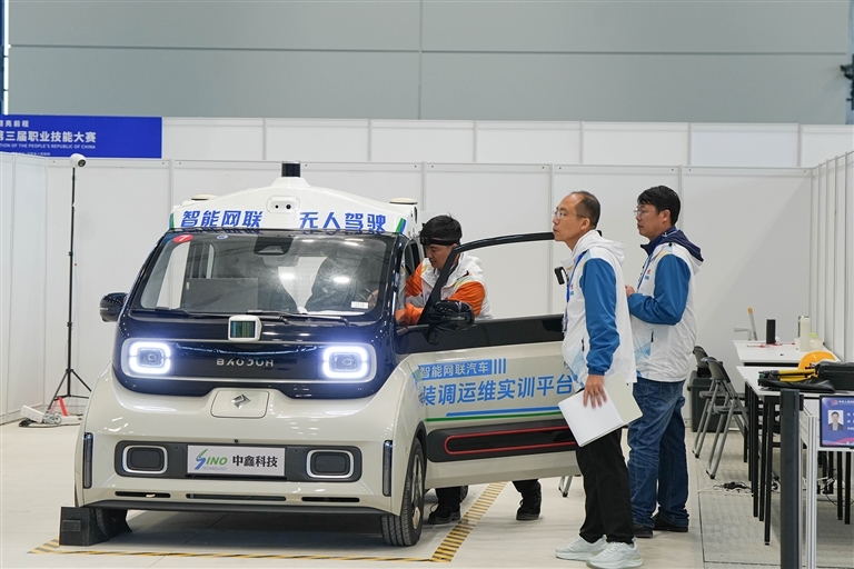 第三届全国技能大赛智能网联汽车装调运维赛场上，河南选手李晓强（左一）正在专心进行比赛。河南日报社全媒体记者 徐聪 摄